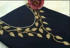 a close up of a black cloth with gold embroidery on it and a pink flower