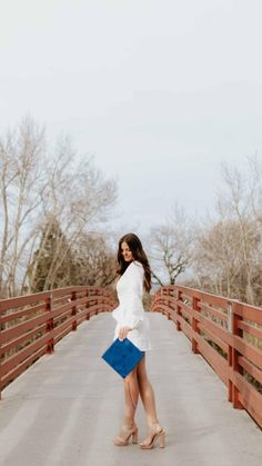 a woman standing on a bridge holding a blue purse