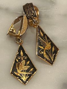 What a unique and stunning pair of vintage, Spanish Damascene Dangle Earrings.  These Clip-On earrings have a lovely curved top piece decorated with a floral motif and under that is a kite shape piece which can swing back and forth.  Each of the dangle pieces has a different lovely scene, one features a bird with its wings spread open in flight in front of a flowering plant and the other has an insect which looks like a dragonfly or butterfly.  A truly delightful pair! The earrings are about 1.25 inches long.  They are light weight and comfortable to wear. FREE SHIPPING RETURNS ACCEPTED This item will be shipped in a gift box with bow. Please let me know if you have any questions!  I am always happy to hear from you! If you have a moment, please take a look at my others items right here on Floral Motif, Lovely Gift, Clip On Earrings, Jewelry Earrings Dangle, Planting Flowers, Insects, Flight, Gift For Her, Dangle Drop Earrings