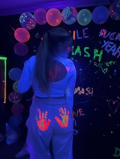 a woman standing in front of a wall with neon hands and hand prints on it