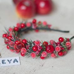 a red wreath with berries and greenery sits on a table