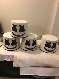 four white cups with black designs on them sitting on top of a table next to papers