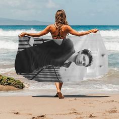 a woman is walking on the beach with a towel over her head and there is an image of a man