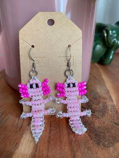 a pair of pink beaded earrings sitting on top of a wooden table