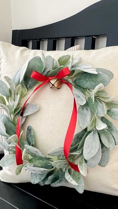 a white pillow with a red ribbon around it and a wreath on the front of it