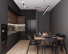 a modern kitchen with black cabinets and wood flooring, along with a dining table set for four