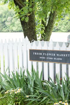 a white picket fence with a sign that says fresh flower market and bed - stems blooms