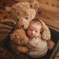 a baby in a box with a teddy bear next to it's head on its chest