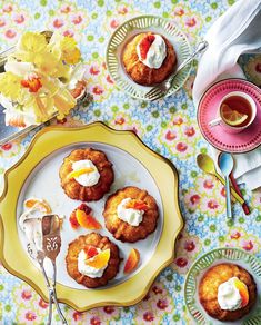 a table topped with plates and cups filled with pastries on top of a floral cloth