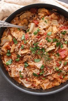 a bowl filled with cabbage and meat on top of a table