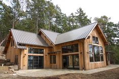 a large wooden house with metal roofing in the woods