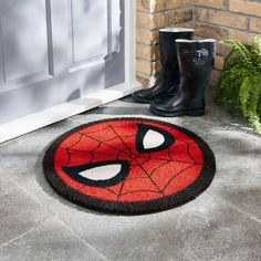 a door mat with a spiderman face on it next to a pair of boots