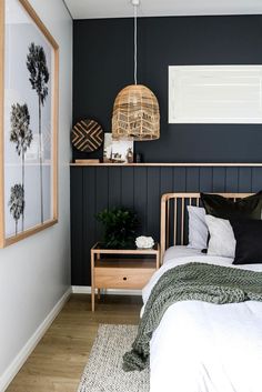 a bedroom with black walls and white bedding, wooden nightstands and plants on the wall