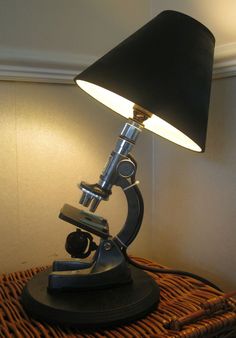 a microscope lamp sitting on top of a wicker table next to a black shade