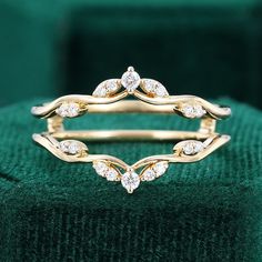 a gold ring with three diamonds on it sitting on top of a green velvet cushion