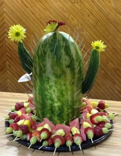 a cactus made out of fruits and vegetables on a plate with flowers in the middle