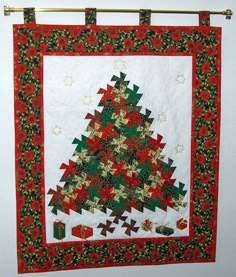 a quilted christmas tree hanging on the side of a wall in front of a white wall