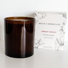 a candle sitting next to a box on a white counter top with the candle in front of it