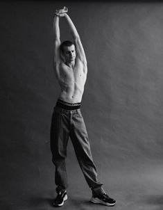 a man with no shirt is holding his arms up in the air while posing for a black and white photo