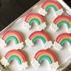 decorated cookies in the shape of rainbows and clouds on a cookie sheet with white icing