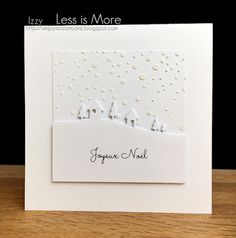 a handmade christmas card with houses and snow on the hill, which reads joyfully less is more