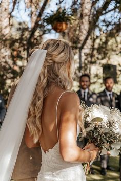 the bride is walking down the aisle with her bouquet in hand as she looks on