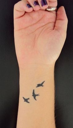 a woman's wrist tattoo with three birds on her left arm and one bird on the right hand