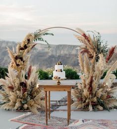 a table with two cakes on it and some flowers