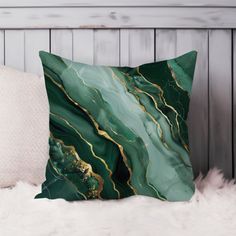 a green and gold marble pillow sitting on top of a white furnishing area