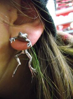 a close up of a person's ear with a frog earrings attached to it