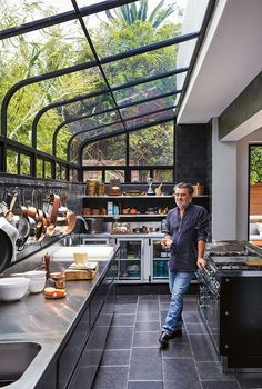 a man standing in a kitchen next to a stove top oven and counter with pots on it