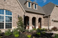 a large brick house with lots of windows and plants in front of the door area