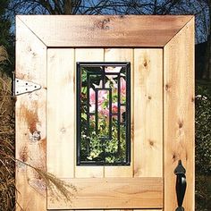 a wooden box with a metal window in the center and flowers on it's side