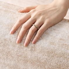 a woman's hand with a ring on top of a carpeted area,