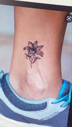 a woman's foot with a small flower tattoo on the side of her ankle