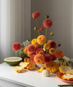 an arrangement of flowers and fruit on a table