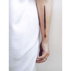 a person with a tattoo on their arm holding a knife in one hand and an ink pen in the other