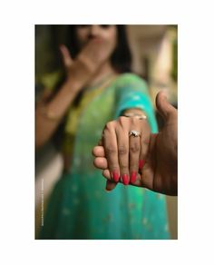 two people holding hands with red and blue nails on their fingers in front of a woman's face