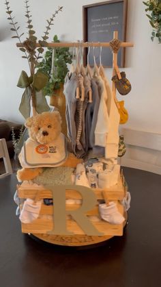 a teddy bear sitting on top of a table next to clothes hanging from a rack