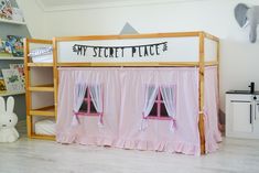 there is a bunk bed with pink curtains on the top and bottom tiers in front of it