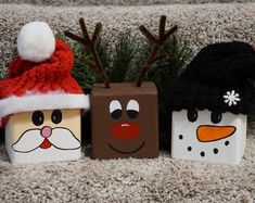 three small boxes decorated like santa claus, snowman and reindeer faces on carpeted area