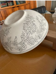 a white vase sitting on top of a wooden table