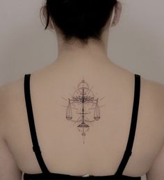 the back of a woman's neck with a tattoo on it that has scales and an hourglass