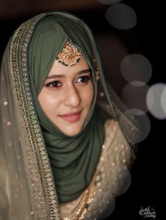 a woman wearing a green hijab and gold jewelry