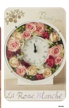 a white clock with pink and red roses on it's face is in front of a thank you card