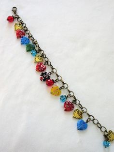 "This heart charm bracelet is made with multi-colored millefiori hearts, gold tone hearts, blue crystals, Czech faceted red glass and brass metals. It is adjustable along the chain from 7 to 8\". At random charms make each bracelet slightly different. This bracelet will be slipped into an organza bag and shipped in a bubble mailer." Multicolor Heart Charm Bracelet, Adjustable Multicolor Charm Bracelet With Heart Beads, Multicolor Heart Charm Bracelet For Jewelry Making, Multicolor Heart Beads Bracelet For Jewelry Making, Multicolor Metal Jewelry With Heart Charm, Multicolor Metal Jewelry With Heart Beads, Multicolor Heart Beads Jewelry In Czech Glass, Multicolor Czech Glass Jewelry With Heart Beads, Irish Cross