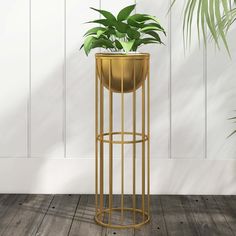 a potted plant sitting on top of a metal stand next to a white wall