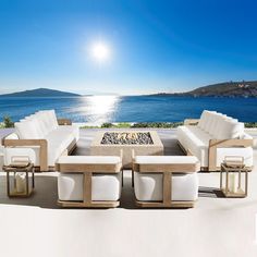 an outdoor living room with white furniture overlooking the ocean