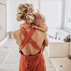 a woman with her back to the camera, hugging another woman's shoulders in a bathroom