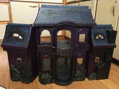 a purple doll house sitting on top of a hard wood floor